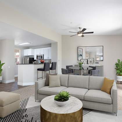 a living room with a grey couch, a coffee table, and a ceiling fan.
