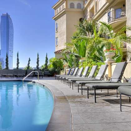 a pool area with lounge chairs and a tall building in the background.