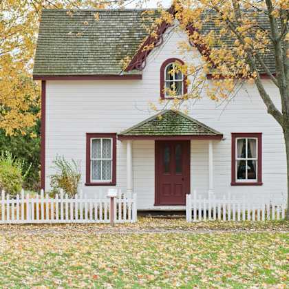 a white house with a red door and a green roof.