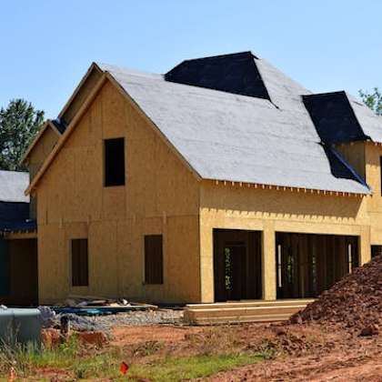 a house under construction with a grey roof and wooden walls.