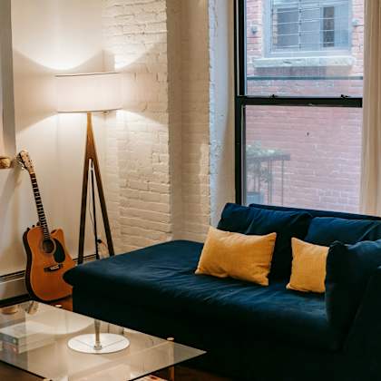 a living room with a blue couch and a guitar hanging on the wall.