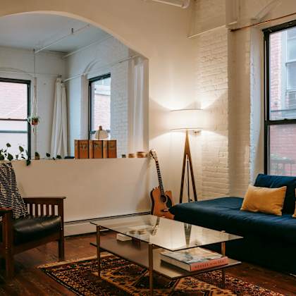 a living room with a guitar on the wall and a blue couch.