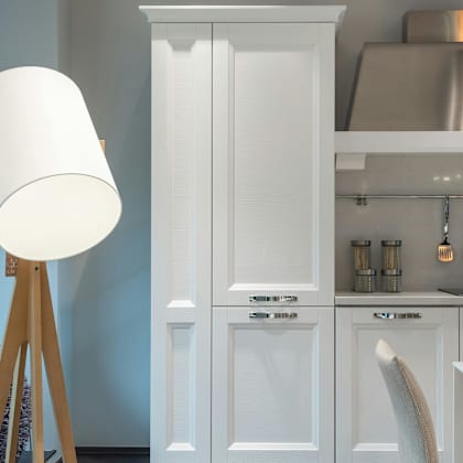 a white lamp stands next to a white cabinet in a kitchen.