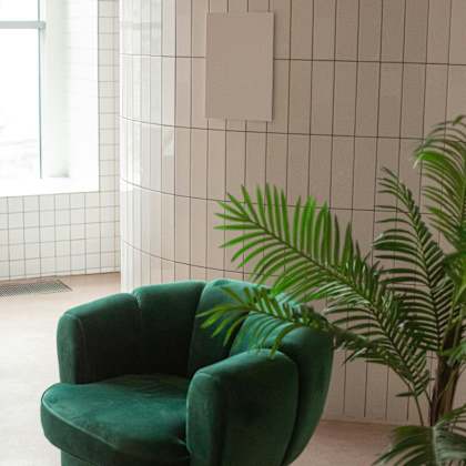 a green chair is in front of a tiled wall.