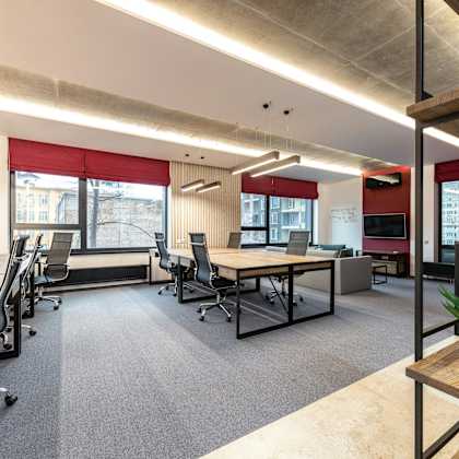 a modern office space with desks, chairs, and a plant.