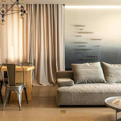 a modern living room with a grey couch, a wooden table, and a metal chair.