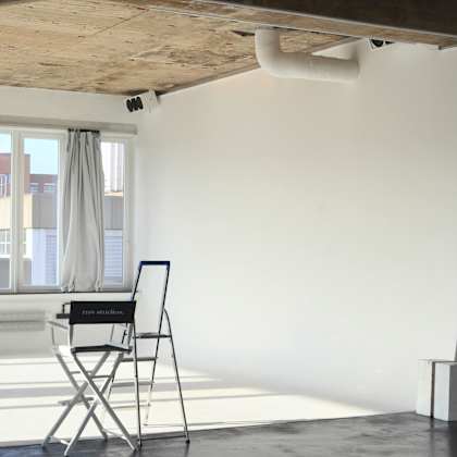 a chair with a laptop on it is in a room with a window.