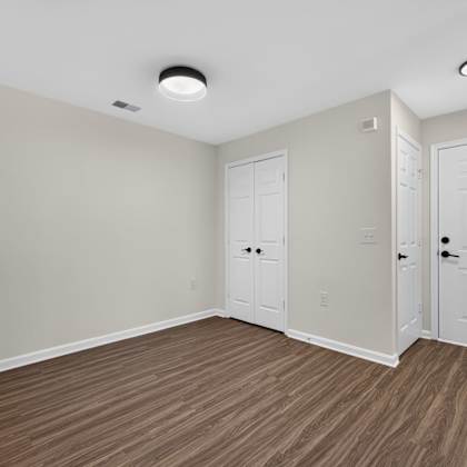 a room with white doors and brown flooring.