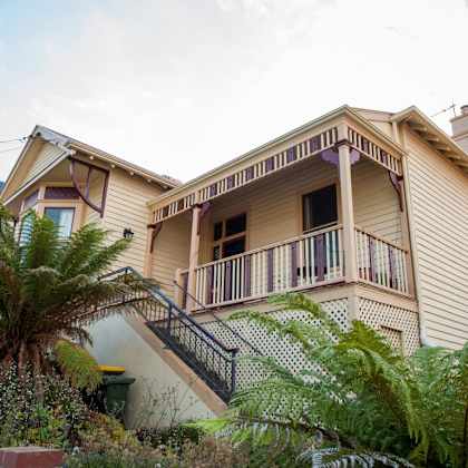 a yellow house with a balcony and a palm tree