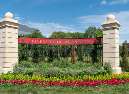 a sign for the university of minnesota with flowers in front of it