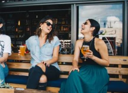 two women and a man sitting on a bench with drinks at The Mark at Dulles Station, Herndon, VA