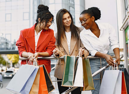 Three women examining the contents of their shopping bags.