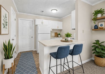 A kitchen with a white fridge and two blue chairs.