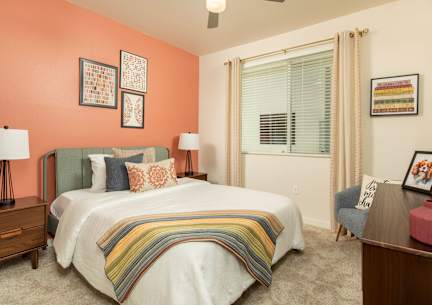 A bedroom with a bed, nightstand, and chair.