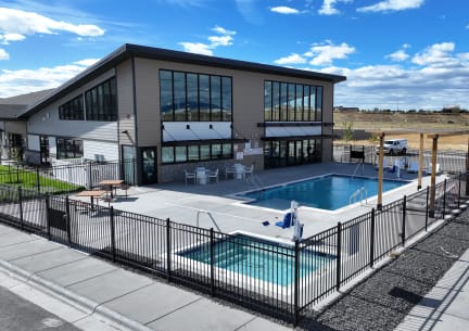 a swimming pool in front of a building with a patio and a poolside building