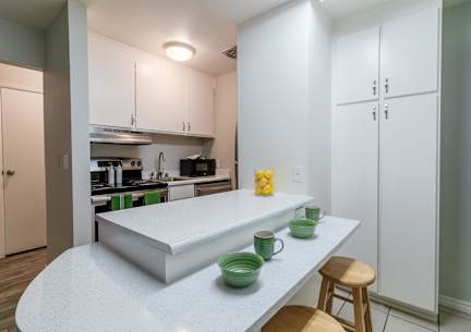 a kitchen with white cabinets and a white counter top with two stools
