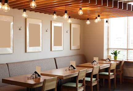 A restaurant with wooden tables and chairs, and framed pictures on the wall.