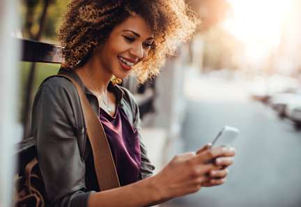 A woman with curly hair is looking at her phone.