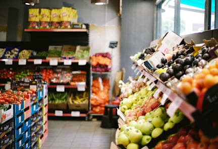A fruit stand in a grocery store with apples and oranges.