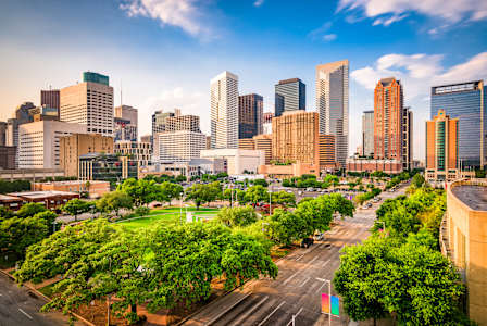 A cityscape with tall buildings and a green park in the foreground.