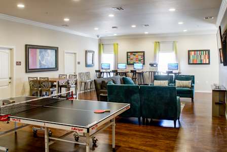 A ping pong table is in the middle of a room with a green couch.