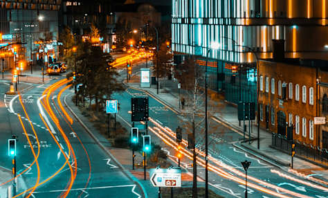A city street at night with cars driving on the road.