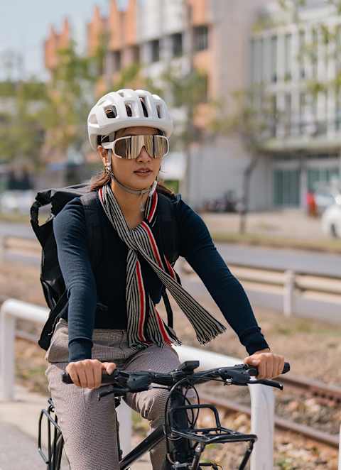 A woman wearing a helmet and sunglasses is riding a bicycle.