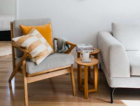 A living room with a chair, a sofa, and a wall decoration.