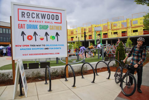 a man on a bike in front of a rockwood market hall sign