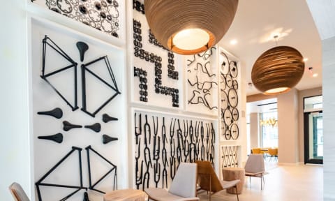 the lobby of a hotel with chairs and a wall filled with art