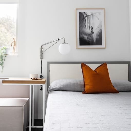 a bedroom with a bed with orange pillows and a window