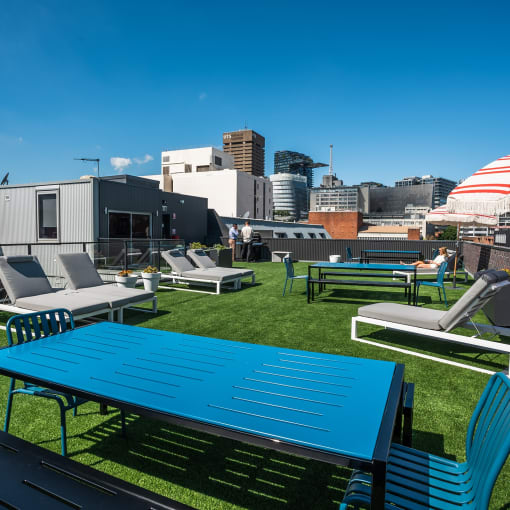 a rooftop patio with tables and chairs and a city in the background