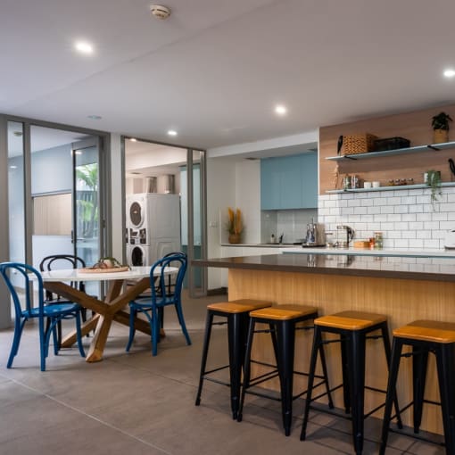 a kitchen with blue cabinets and a bar with four stools