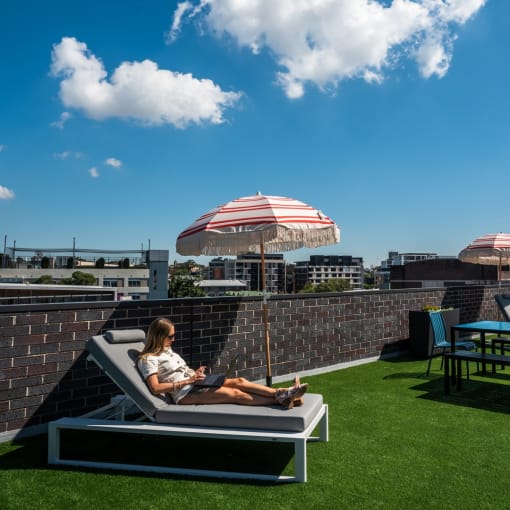 a woman sitting on a lounge chair on a roof top