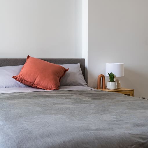 a bedroom with a bed and an orange pillow