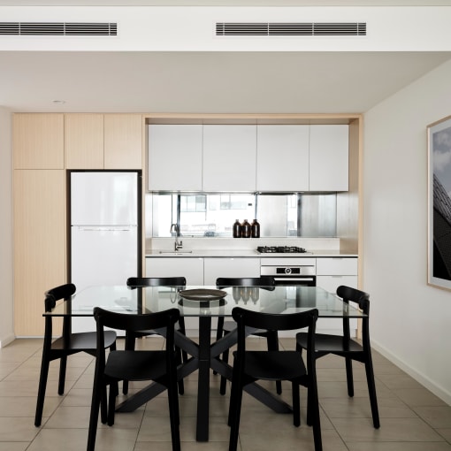 a kitchen and dining room with a glass table and black chairs