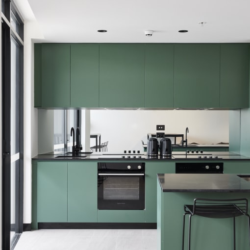 a kitchen with green cabinets and black counter tops and a sink