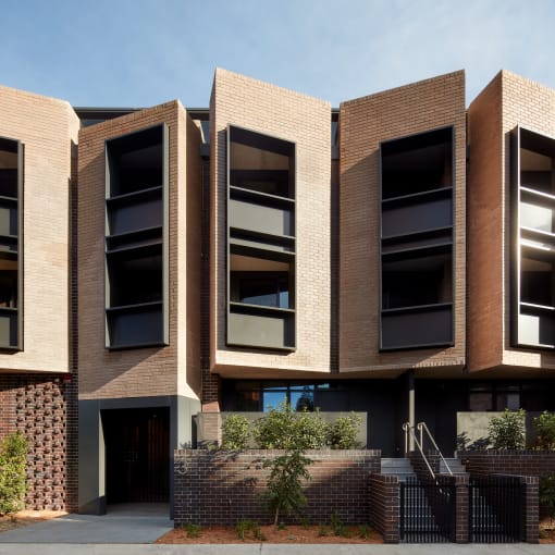 a three story brick apartment building with black windows