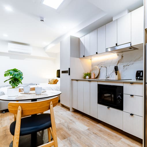 a kitchen with white cabinets and a table and a refrigerator