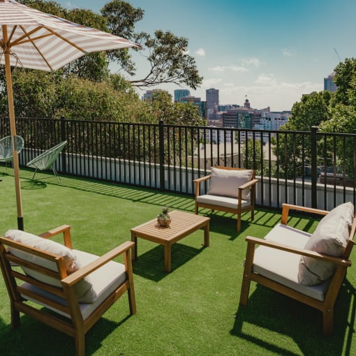 a rooftop terrace with lawn chairs and an umbrella