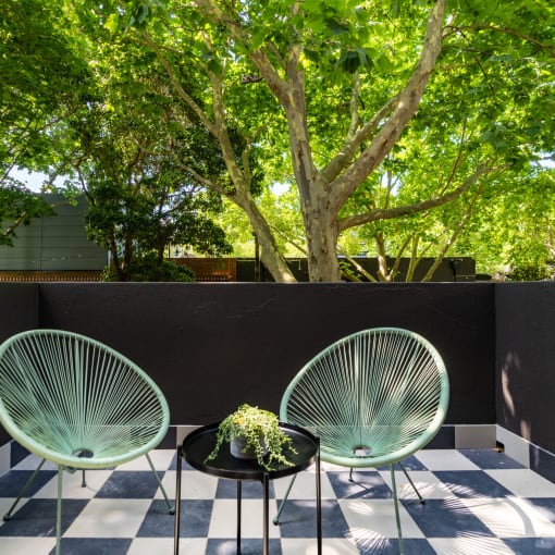 two chairs on a patio with trees in the background