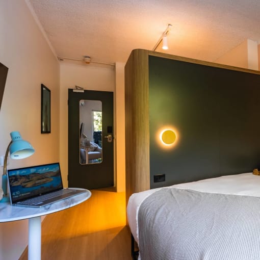 a bedroom with a bed and a laptop on a desk