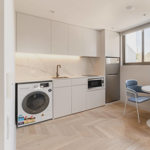 a kitchen with a washing machine and a table with chairs