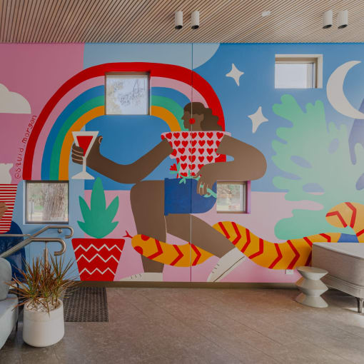 a colorful mural in a room with couches and potted plants