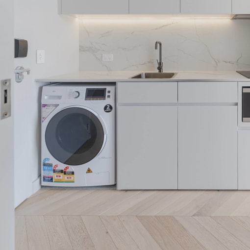 a white kitchen with a washing machine and a sink