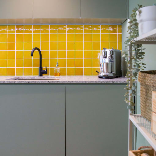 a kitchen with green cabinets and yellow tiles