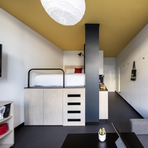 a bedroom with a bunk bed and a desk in a room with a yellow ceiling