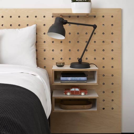 a bed with a wooden headboard and a shelf with a lamp and a clock