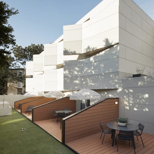 a terrace with a table and chairs in front of a white building