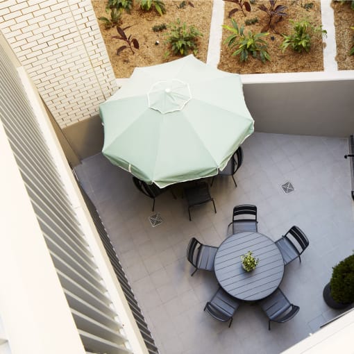 a patio with a table with a green umbrella